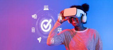 Gülümseyen bir kadın dijital kalite kontrol simgeleriyle çevrili sanal gerçeklik kulaklığıyla modern yönetim sistemlerine teknolojinin entegrasyonunu gösteriyor. XDMCP