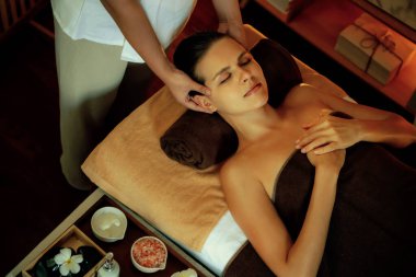 Beyaz kadın stres önleyici kafa masajı yapmaktan ve lüks otel veya otelde sıcak mum ışığında yüz güzelliği eğlencesi yapmaktan zevk alıyor. Sessiz.