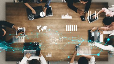 Çeşitli dijital cihazlar üzerinde işbirliği yapan, modern bir çalışma alanında veri analizi ve görselleştirme teknikleri sergileyen farklı bir ekibin hava görüşü. Xenic