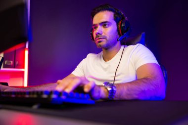 Akıllı oyun kurucusu, dijital neon ışıklandırma stüdyosundaki sosyal medya uygulamasında başkalarıyla iletişim kurmak için kulaklık ve mikrofon kullanan takım üyeleriyle konuşuyor. Tahmin et..