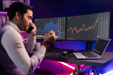 Tüccar akıllı işadamı komisyoncuyu ya da ortağını arıyor, modern evde kârlı bir finans teknolojisi olan neon aydınlatma ofisindeki bilgisayardaki dinamik borsa yatırımlarını analiz ediyor. Tahmin et..