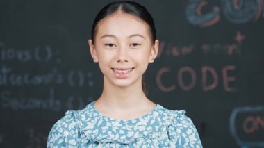 Mühendislik dersiyle tahtaya bakarken kameraya bakan beyaz tatlı bir kız. Kamera sistemi koduna gülümseyen yetenekli öğrenci STEM teknoloji sınıfında arkada yazılı. Öğretim