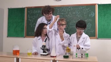 Amerikalı bir kız renkli sıvıyı incelerken erkek beher içine solüsyon döker. Enerjik öğrenci, öğretmenler çocukları keşfederken ve yenilikleri keşfederken arkadaşının deney yapmasına destek oluyor. Pedagoji.