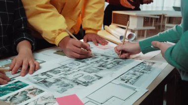 Parlak bir ofis ortamında ekip çalışması ve yaratıcılığı yansıtan, plan ve planlar üzerinde işbirliği içinde çalışan ve çizim yapan dinamik bir sahne. SACTR