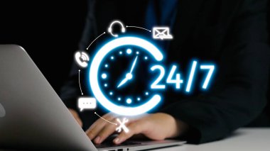 Modern bir çalışma alanında teknolojiyle ilgilenen bir iş adamı, 24 saatlik hizmeti ve iletişim ve bağlantı simgelerini destekler. Dörtgen