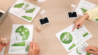 Eko evi projesini yel değirmeni tasarım modeli ve karbon ayak izini azaltmak için yeşil enerji kullanım grafiği ile toplantı masasında tartışan harika bir iş ekibi. Dünyayı kurtarın. Eline odaklan. Tanımlama.