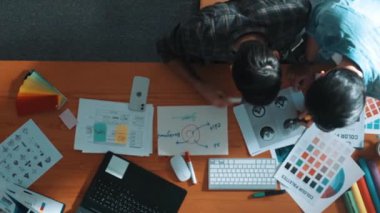 Akıllı tasarımcının renkli paletlerden renk seçmesine yardım ederken yukarıdan aşağı görünümü. Dizüstü bilgisayardan logoya bakarken birlikte çalışan ve planlayan iş adamlarının hava görüntüsü. Sempozyum.