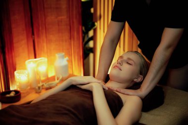 Beyaz kadın müşteri stres önleyici spa masajının keyfini çıkarıyor ve lüks otel ya da otelde sıcak mum ışığında güzellik teniyle eğleniyor. Sessiz.