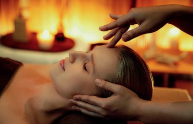 Kafkasyalı kadın stres önleyici kafa masajını yapmaktan ve lüks otel veya otelde sıcak mum ışığında yüz güzelliğini şımartmaktan zevk alıyor. Sessiz.