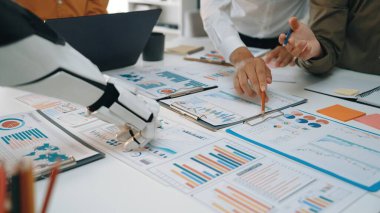 Robot bir elin, karar verme ve strateji verimliliğini arttırmak için veri tabloları ve grafiklerini analiz etmede insan meslektaşlarına yardım ettiği modern bir iş toplantısı sahnesi.