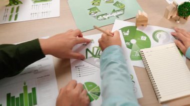 Mükemmel iş adamları, yeşil enerji grafiği kullanımı olan karmaşık bir masada eko ev projesini tartışıyor alternatif enerjiyi seçiyor ya da analiz ediyor, karbonu azaltıp dünyayı kurtarıyor. Eline odaklan. Tanımlama.