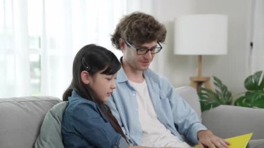 Beyaz bir baba ve tatlı bir kız kanepede otururken masal kitabı okuyorlar. Mutlu bir baba, sevimli bir Amerikan çocuğuna, birlikte zaman geçirirken hayal gücünün gelişmesi için hikaye anlatıyor. Pedagoji.