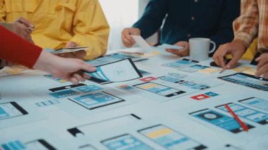 Bir grup profesyonel, ağ ve uygulama geliştirme, takım çalışması ve yaratıcılık için kullanıcı arayüzü prototipleri ve modellerini analiz ederek, parlak bir ofis alanında işbirliği yapmaktadır. SACTR