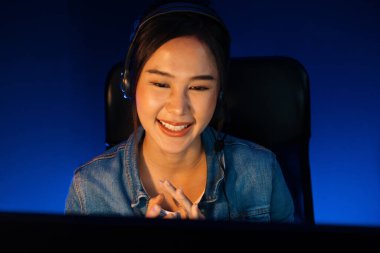 Sunucu kanalı Asyalı etkileyicisi canlı yayında konuşuyor. Sosyal medyada kulaklık takıyor, bilgisayar kaydı yapıyor, dinleyicileri selamlıyor ve Neon Modern Stüdyoları 'nda online olarak koçluk yapıyor. Taktik.