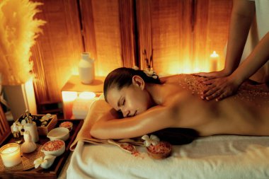Lüks spa salonlarında sıcak mum ışığında cilt bakımı yaptıran kadın müşteri. Sağlık Spa vücut fırçasında tuz temizleme güzellik tedavisi. Sessiz.