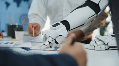 Takım üyeleriyle çarpışan robotik bir kolun yer aldığı modern bir iş toplantısı. Sahne, profesyonel bir çalışma alanı dahilinde teknolojide işbirliği ve yeniliğin altını çiziyor.