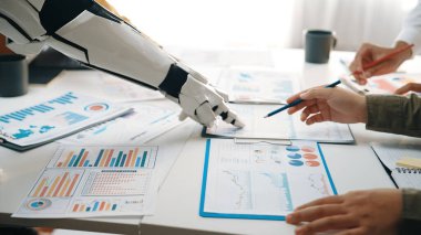 Bir robotik kol, modern bir çalışma alanında teknoloji ve insan çabası arasındaki işbirliğini gösteren, iş analizi belgeleriyle bir masada etkileşime girer.