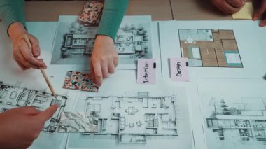 Detaylı mimari planlar ve renkli tasarım örneklerinin yer aldığı yaratıcı bir çalışma alanı. Çalışan eller modern iç mekanlar için tasarım planlama sürecini gösteriyor. SACTR