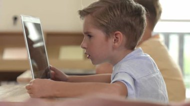 Bilgisayar üzerinde çalışan beyaz çocuğun yan görüntüsü. Mühendislik ödevi sırasında. Çekici çocuklar bilgisayar yazılımı kullanarak yapay zeka ya da programlama sistemini öğreniyor ya da öğreniyor. Pedagoji.