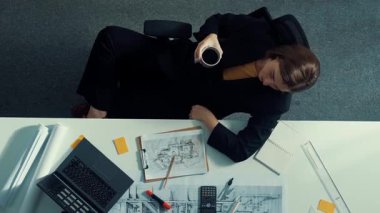 Üst düzey inşaat mühendisi yapışkan notlar yazıyor ve dizüstü bilgisayara bakıyor. Hava görüntüleme mimarı bilgisayar analizi yaparken toplantı masasında oturuyor ve bina yapısını hesaplıyor. Hizalama.