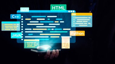 Bir kişi canlı bir dijital ortamda, içinde HTML, ve C 'nin de bulunduğu çeşitli dilleri gösteren, yüzen programlama kodlu bir akıllı telefon bulundurur. Dörtgen