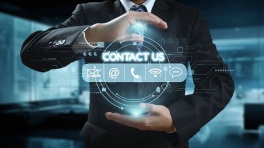 Resmi kıyafet giymiş bir işadamı, temas simgelerini gösteren dijital bir arayüz sergiliyor. Modern ofis geçmişi iletişimi ve ağı vurguluyor. Dörtgen