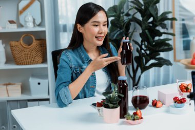 Gülümseyen, güzel Asyalı genç, lezzetli karışık çilek ve kiraz suyu detoksu içeceklerini inceleyen, sosyal medyada özel promosyon satışı için sağlıklı ürünler sergileyen. Taktik.