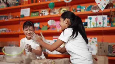 Mutlu çok kültürlü kız ve arkadaşı sanat dersinde çamurlu gömleği birbirine sürmüş. Çeşitli lise öğrencileri çömlek atölyesinde kille oynuyor. Yaratıcı aktivite konsepti. Öğretim