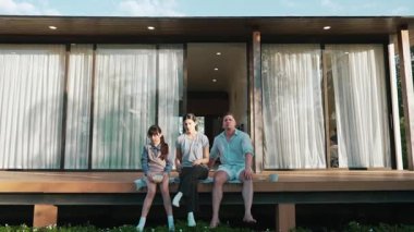 Şirin baba, anne ve kızı birlikte evin bahçesinde oturuyorlar. Ebeveynler, çevre farkındalığıyla ilgili genç nesli iletişim kurmak için açık hava aktivitelerini kullanırlar. Uyumsuzluk.