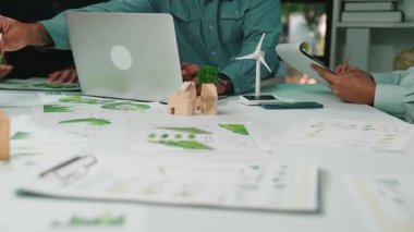 Sürdürülebilir kalkınma stratejilerini tartışan bir grup profesyonel, yenilenebilir enerji modelleri ve yeşil teknoloji raporlarını işbirlikçi bir ofis ortamında analiz ediyor. SACTR