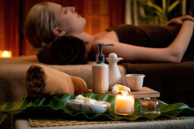 Aromaterapi masajı ambiyansı ya da spa salonu kompozisyon düzeneği bulanık kadınlara odaklı dekor mumları ve spa aksesuarları ile tatil köyü veya otel arka planında keyifli aroma spa masajı yapan. Sessiz.
