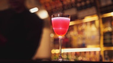 Gülümseyen Asyalı akıllı barmen, lüks tezgah barında bardakla karışık kokteyl hazırlıyor, VIP müşteriyle birlikte gece hayatı sıcak gece kulübü servisinde özel bir içecek hazırlıyor. Vinosity.