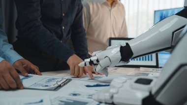 İnsan ve robot işbirliğini gösteren dinamik bir toplantı sahnesi, iş haritaları ve verilerin altını çizen, modern çalışma alanlarındaki takım çalışmalarının geleceğini sembolize eden. Noogenesis