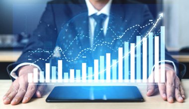 Bir işadamı dijital tablette sergilenen mali verilere odaklanırken, grafikler ve grafikler çağdaş bir ofis ortamındaki büyüme ve performansı gösteriyor. Etki