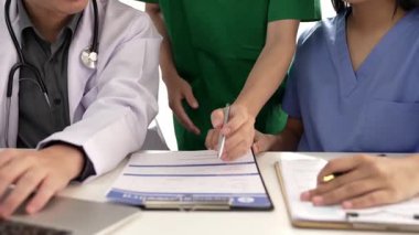 Hastane masasında birlikte çalışan ve tıbbi tedavi planlayan çeşitli profesyonel sağlık görevlileri. Takım çalışması başarılı hastalıklara ve hastalıklara yol açar. Ağır çekim. Katı.