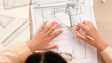 Akıllı mimar ya da akıllı mühendisin ölçüm aracı ve ahşap kalem el kullanarak mimari ofisindeki inşaat isabetinin planının detaylarını yazdığı bir video. Eline odaklan. Tanımlama.