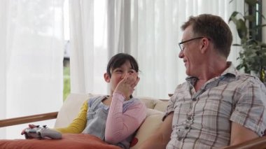 Büyükbaba ve torun birlikte konsol oyunu, eğlence medyası oynuyorlar. Eski kullanım teknolojisi yeni nesil ile iletişim kurar. Nesiller arası uçurum aile bağını güçlendirir. Uyumsuzluk.