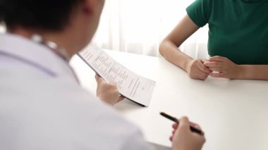 Klinikteki ya da hastane ofisindeki doktor randevusuna katılan hasta, tıbbi tedavi seçeneklerini tartışıyor ve muayene sonuçlarını ya da hastalıkla ilgili tıbbi kayıtları açıklıyor. Ağır çekim. Katı.