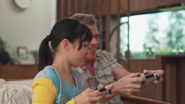 Büyükbaba ve torun birlikte konsol oyunu, eğlence medyası oynuyorlar. Eski kullanım teknolojisi yeni nesil ile iletişim kurar. Nesiller arası uçurum aile bağını güçlendirir. Uyumsuzluk.