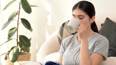 Elinde kahve fincanı olan bir kadın, ders kitabı okur, sosyal ve mesleki teknoloji bilgisini arttırır ya da akıllı bir anne olmak için çocuk yetiştirir. Hayat boyu öğrenme konsepti. Uyumsuzluk.