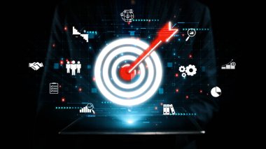 Bu resim, modern teknolojideki etkin stratejileri ve hedef başarıyı sembolize eden çeşitli iş simgeleriyle çevrili, hedefe bir okla vurulan dijital hedefi gösteriyor. Dörtgen