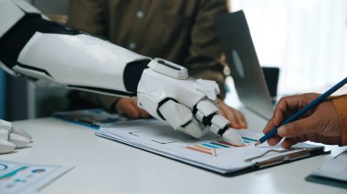 Gösterişli bir ofis ortamında bir insan ve bir robot kol arasındaki dinamik etkileşim, çalışma alanlarındaki işbirliğinin ve teknolojik yeniliğin geleceğini sembolize ediyor. Noogenesis