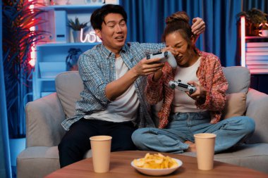 Oyun oynayan mutlu çiftin oturduğu kanepe joystickle oyun oynuyordu. Önden atıştırmalıklar ve kazanmak için gözlerini kapayan içkiler, evdeki modern neon ışıklı oturma odasında eğlenceli bir şekilde meydan okumaydı. İnfobahn.