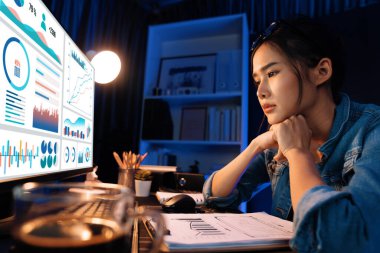 Stresli, genç, güzel Asyalı yaratıcı proje yaratıcısı sosyal medyayla bilgisayar ekranına bakıyor ve planlama kanalı stratejisi geceleri daha fazla neon modern ofiste izleyiciye ulaşıyor. Taktik.