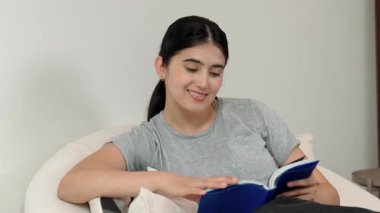 Kanepede oturan bir kadın ders kitabı okuyarak sosyal ve mesleki teknoloji bilgisini artırır ya da akıllı bir anne olmak için çocuk yetiştirir. Hayat boyu öğrenme konsepti. Uyumsuzluk.