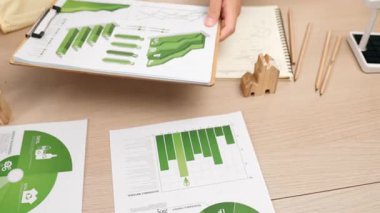 Şirketin gelecekteki EG 'si için yeşil enerji grafiği kullanımına danışmanlık ve analiz yapan iş ekibi. Yel değirmeni modeli, masadaki temiz enerji ve ev bloğu sembolize edilmiş eko evi kullanarak temsil ediliyor. Tanımlama.