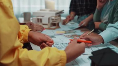 Modern bir ofis ortamında mimari planlar ve modeller üzerinde işbirliği yapan dinamik bir grup, takım çalışması ve tasarım planlamasında yaratıcılık sergiliyor. SACTR