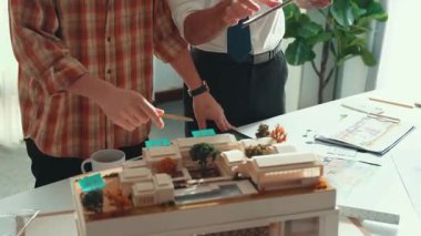 Akıllı mimar ya da inşaat mühendisi bina yapısı fikrini not edip plana yapıştırıyor. Yöneticinin çeşitli meslektaşları ve ev planlarıyla birlikte çalıştığı hava görüşü. Hizalama.