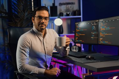Bilgisayar ekranındaki yazılım geliştirme kodlarında kahve fincanı tutan akıllı bilişim geliştiricisi profili. Program güncellemesi internet sitesi verilerini neon ışığı siber ofisinde sunuyor. Tahmin et..
