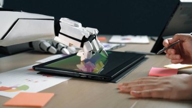 Gelecekçi bir robot el, renkli yapışkan notlar ve tasarım belgeleri, yenilik ve teknolojiyi ön plana çıkaran parlak ve modern bir çalışma alanı üzerinde dijital tabletle etkileşim içindedir.